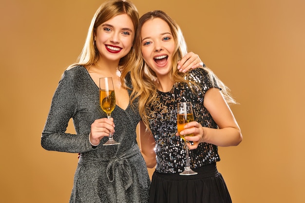 Happy smiling women in stylish glamorous dresses with champagne glasses