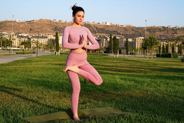 Happy sportive woman practicing yoga outdoors