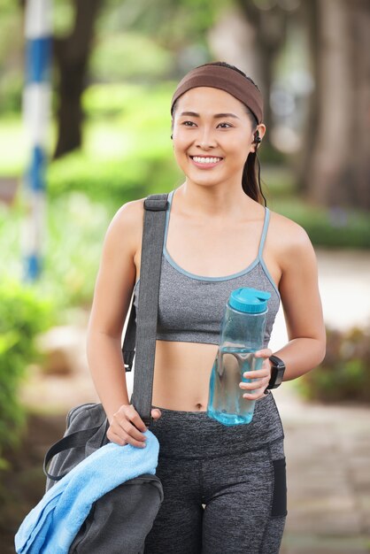 Happy sportswoman with bottle in park