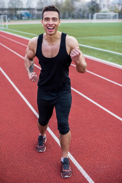 Happy strong man celebrating his success on running track