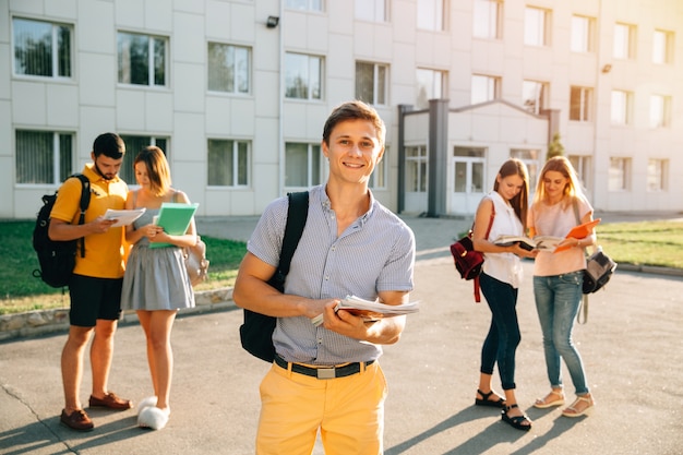 Free photo happy student with note-books and backpack smiling while standing