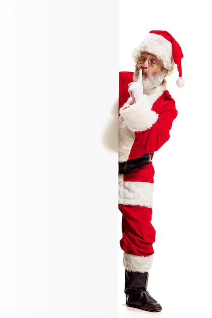 Happy surprised Santa Claus pointing on blank advertisement wall