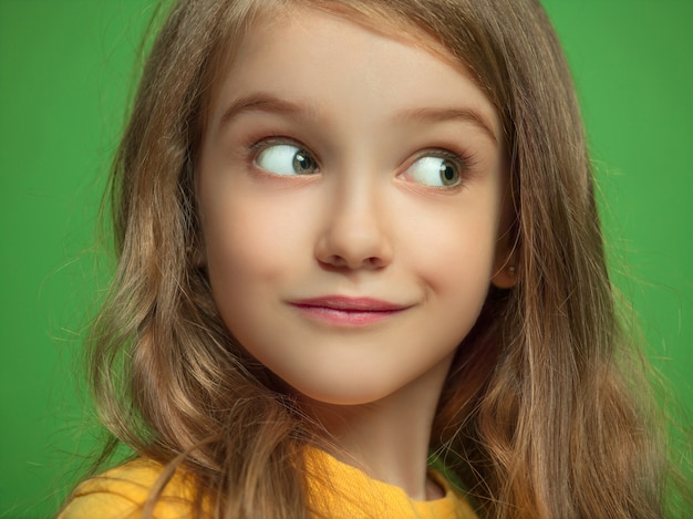 The happy teen girl standing and smiling against green background.