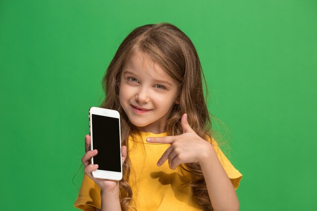 The happy teen girl standing and smiling against green background.