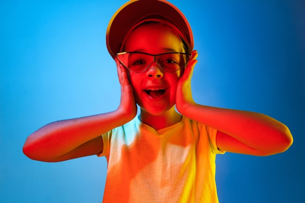 Free photo happy teen girl standing and smiling isolated on trendy blue neon studio