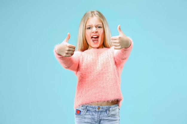 Happy teen girl standing, smiling isolated on trendy blue  space. Beautiful female portrait. Young satisfy girl with sign ok. Human emotions, facial expression concept