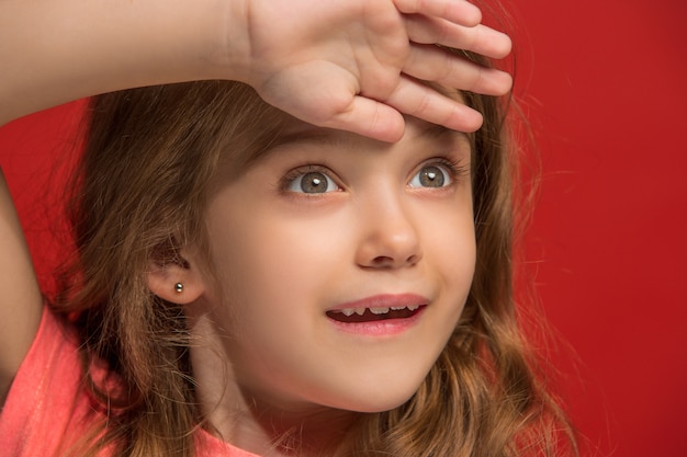 Happy teen girl standing, smiling isolated on trendy red studio background.  Young satisfy girl.  Front view.