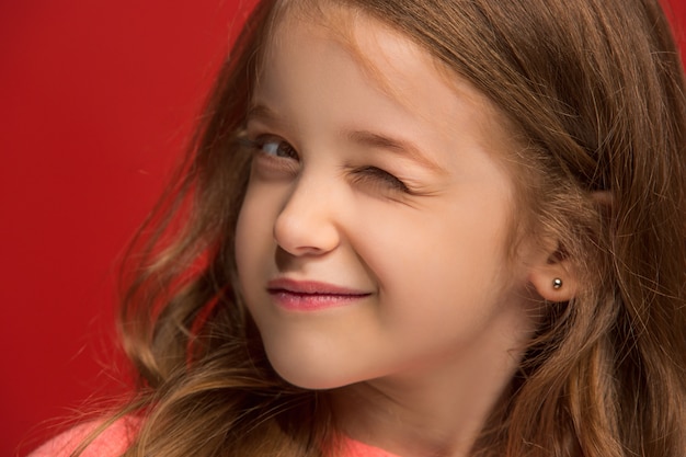 Happy teen girl standing, smiling isolated on trendy red studio background.