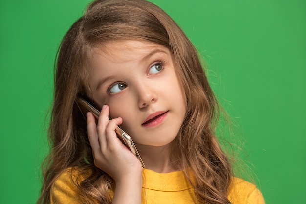 Happy teen girl standing, smiling with mobile phone over trendy green studio background