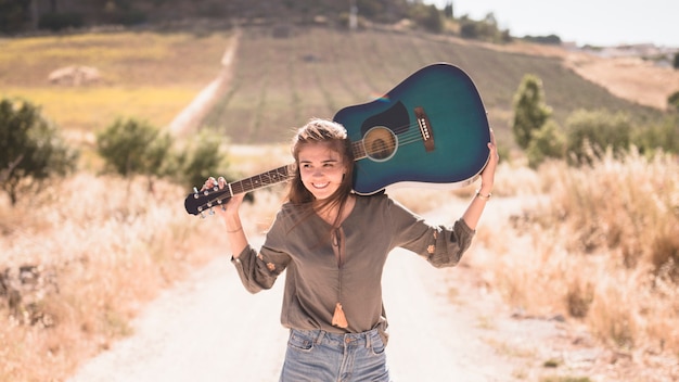 Free Photo happy teenage girl holding guitar at outdoors