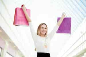 Free photo happy teenage girl pleased with her purchases holding pink shopping bags