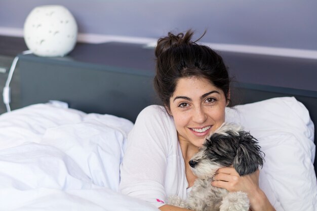 Happy teenager posing with her dog in the bedroom