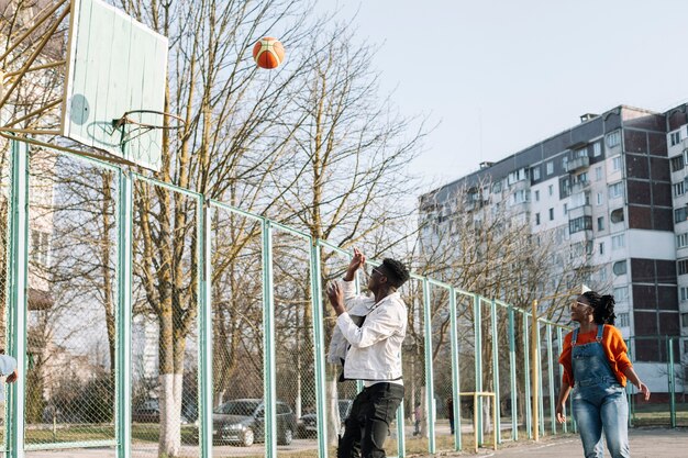 Happy teenagers playing basketball outdoors