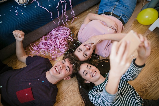 Happy teenagers taking a selfie laying on  the floor