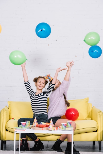 Free Photo happy two girls enjoying throwing balloons in the air on party