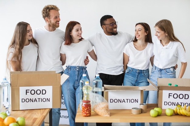 Happy volunteers hugging each other while preparing donation boxes