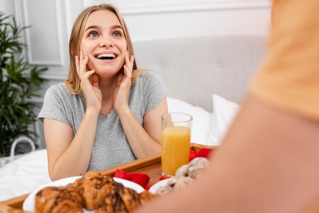 Happy woman being surprised with breakfast in bed