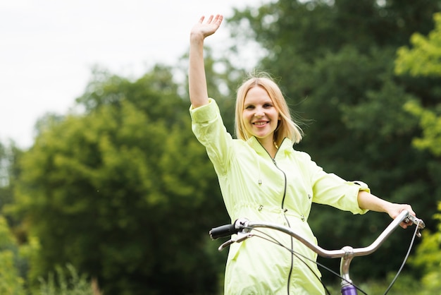 Free Photo happy woman on bicycle waving 