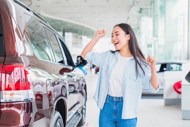 Happy woman in car dealership