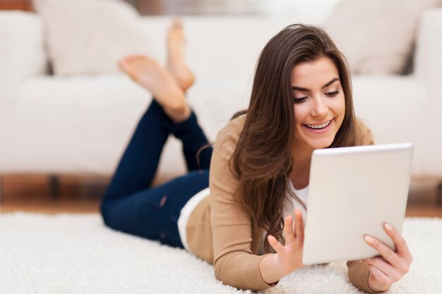 Happy woman on carpet using digital tablet 
