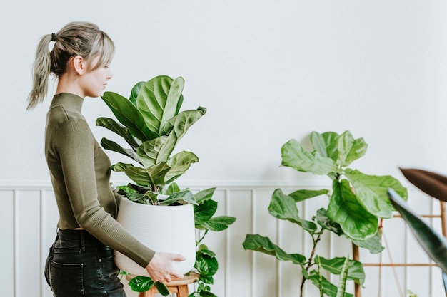 Free Photo happy woman carrying a houseplant