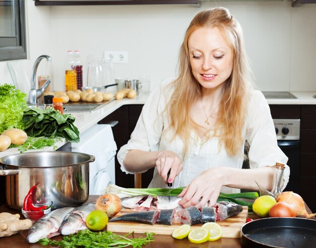 Happy woman cutting seabass fish