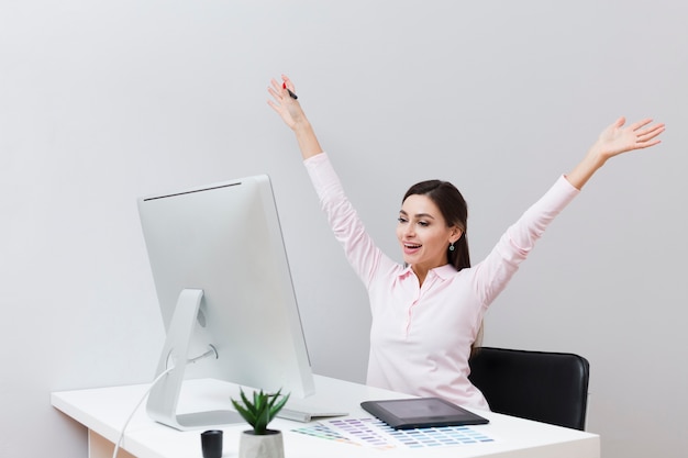 Happy woman at desk looking at computer