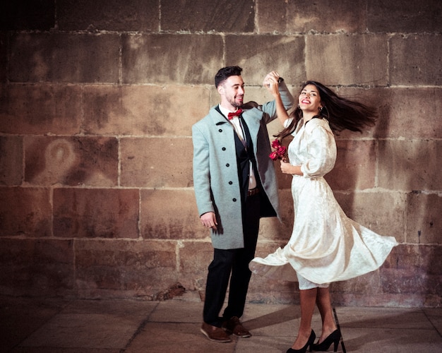 Happy woman in dress dancing with man in street 