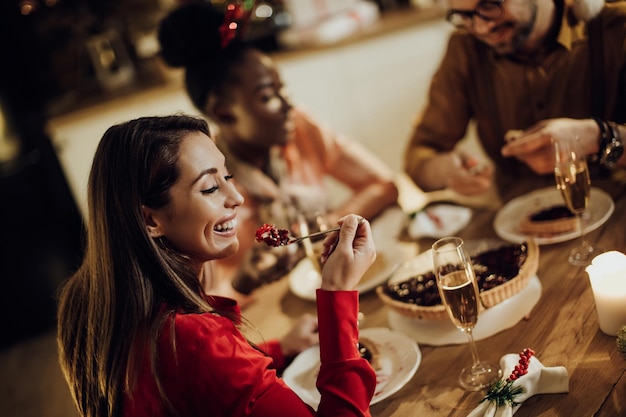 Free Photo happy woman eating cheery pie while having christmas dinner with friends at home