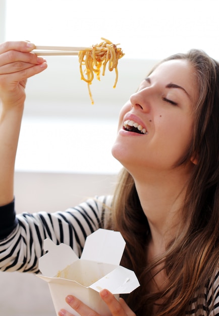 Free photo happy woman eating noodles