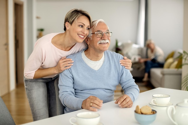 Happy woman embracing her senior father at home