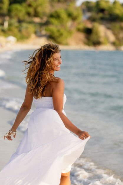 Happy woman feeling carefree while running in sundress at the shore during summer day