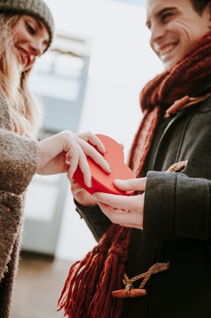 Free photo happy woman gifting heart shaped box to man