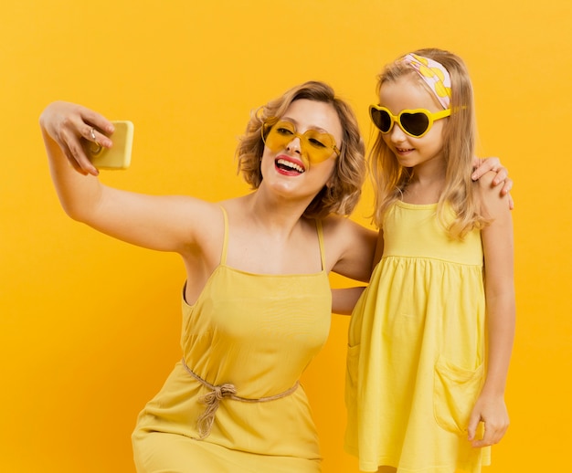 Happy woman and girl taking a selfie while wearing sunglasses