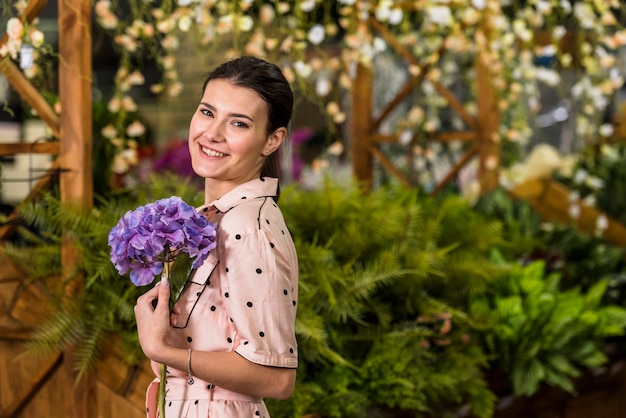 Happy woman holding blue flower in green house