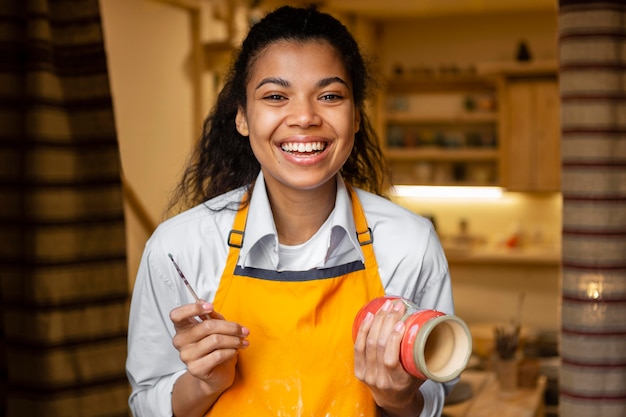 Free photo happy woman holding clay pot