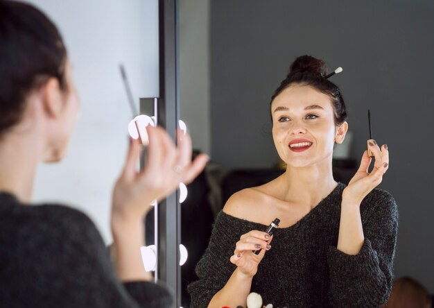 Happy woman holding mascara wand