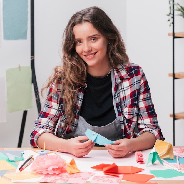 Free photo happy woman holding origami craft looking at camera