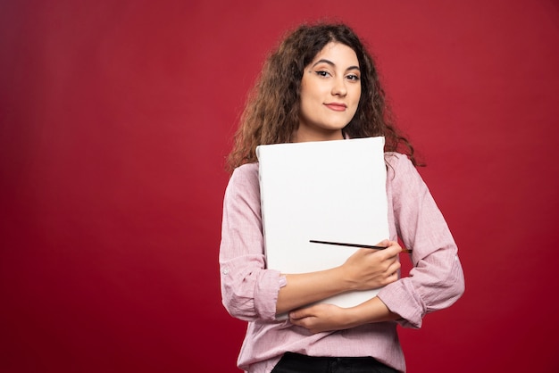 Happy woman holding paintbrush and canvas.