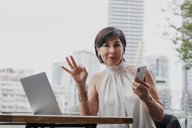 Free photo happy woman holding a phone on urban background