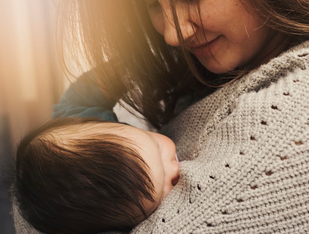 Happy woman holding sleeping baby in arms