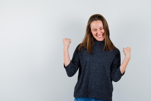 The happy woman is raising up her fists on white background