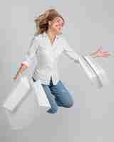 Free photo happy woman jumping and posing while holding lots of shopping bags