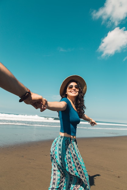 Free photo happy woman leading man through sand of beach