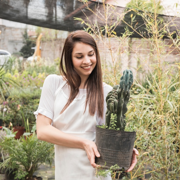 Free Photo happy woman looking at cactus in greenhouse