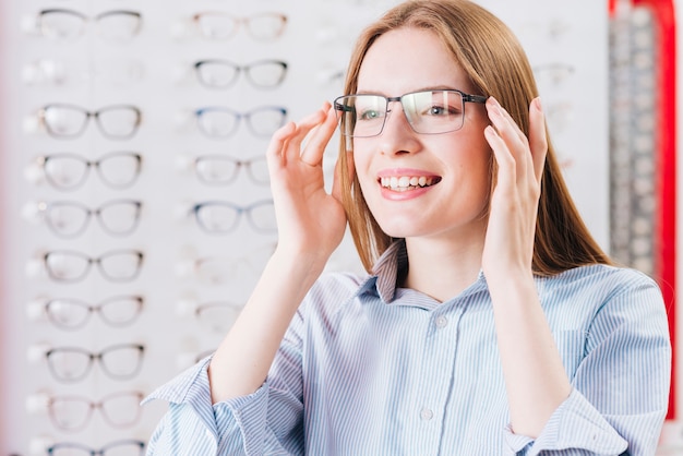 Free photo happy woman looking for new glasses at optometrist