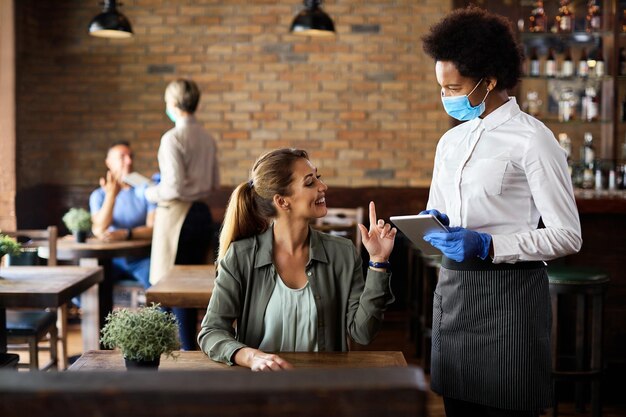 Happy woman making an order while talking to black waitress in a cafe