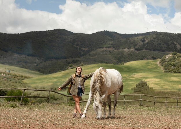 Happy woman petting horse full shot