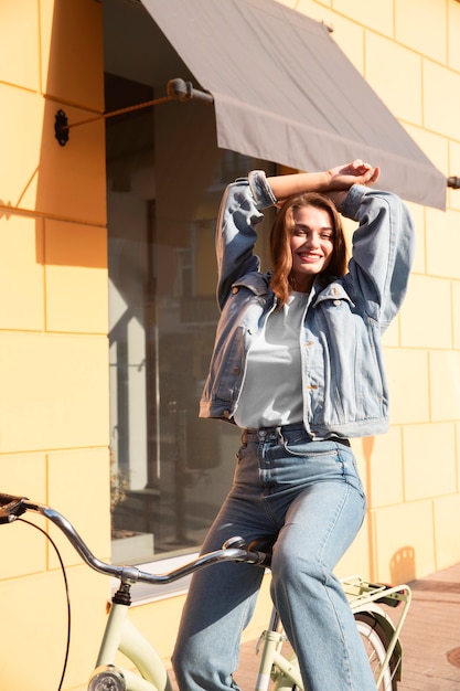 Free photo happy woman posing on her bike in the street