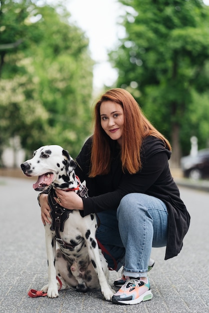 Free photo happy woman posing and playing with her dalmatian dog during a urban city walk